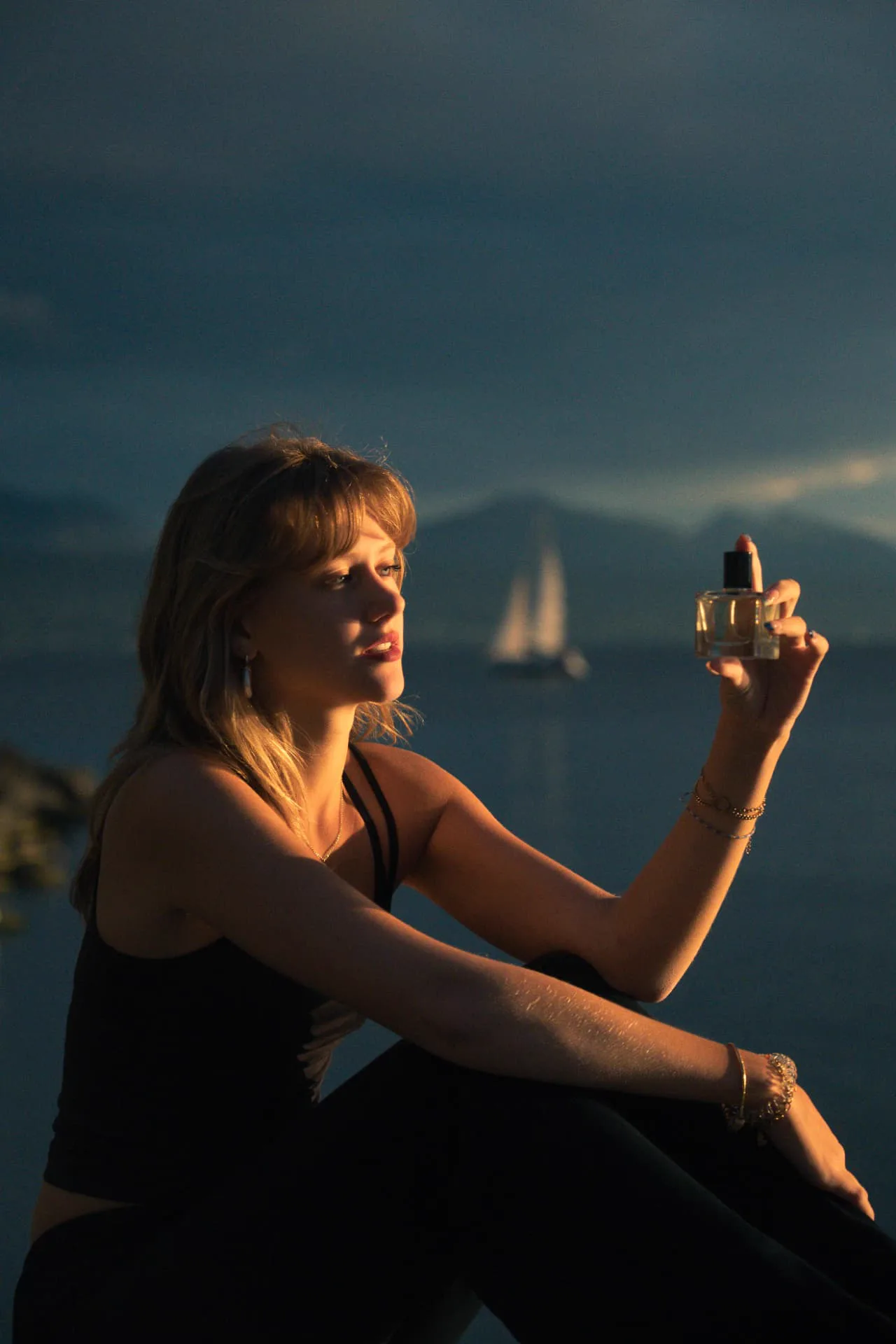 Flakon L’Isolée von Helvé Noé in einer Hand am Wasser im Sonnenuntergang